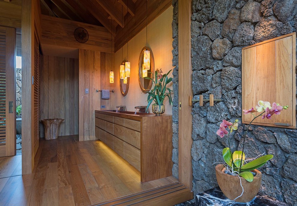 Esempio di una stanza da bagno padronale tropicale con ante lisce, ante in legno chiaro, pareti beige, pavimento in legno massello medio, lavabo rettangolare e top in legno