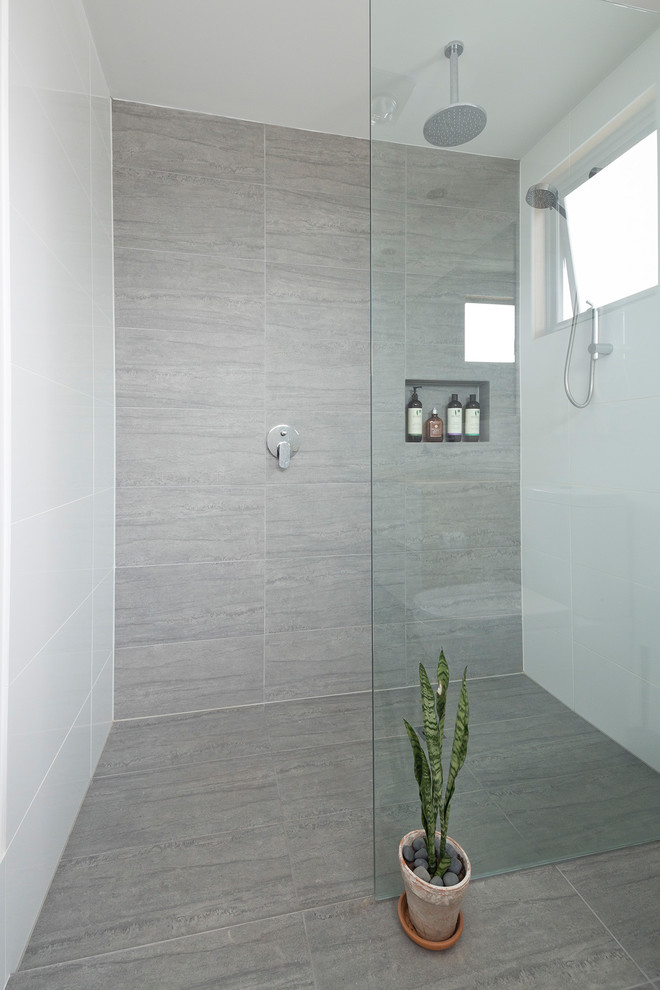 Cette image montre une salle de bain minimaliste avec des carreaux de porcelaine, un sol en carrelage de porcelaine, un lavabo posé et une cabine de douche à porte battante.