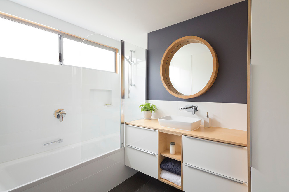 Photo of a small modern bathroom in Perth with a built-in sink, wooden worktops, a built-in bath, a shower/bath combination, white tiles, ceramic tiles, white walls, ceramic flooring and white cabinets.