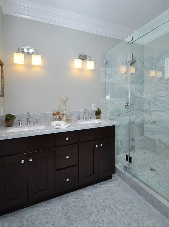 Mid-sized elegant 3/4 gray tile and marble tile ceramic tile and gray floor doorless shower photo in Orange County with raised-panel cabinets, brown cabinets, a two-piece toilet, gray walls, an undermount sink, marble countertops, a hinged shower door and gray countertops