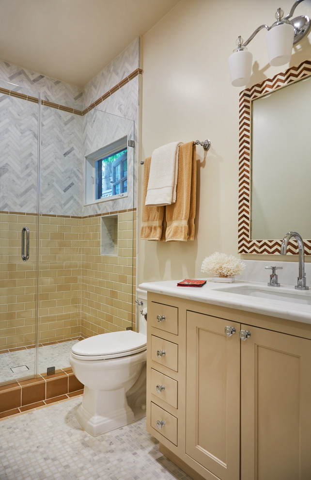 Пример оригинального дизайна: ванная комната в классическом стиле с фасадами с утопленной филенкой, желтыми фасадами, душем в нише, белой плиткой, желтой плиткой, бежевыми стенами, полом из мозаичной плитки, душевой кабиной, врезной раковиной, серым полом и душем с распашными дверями
