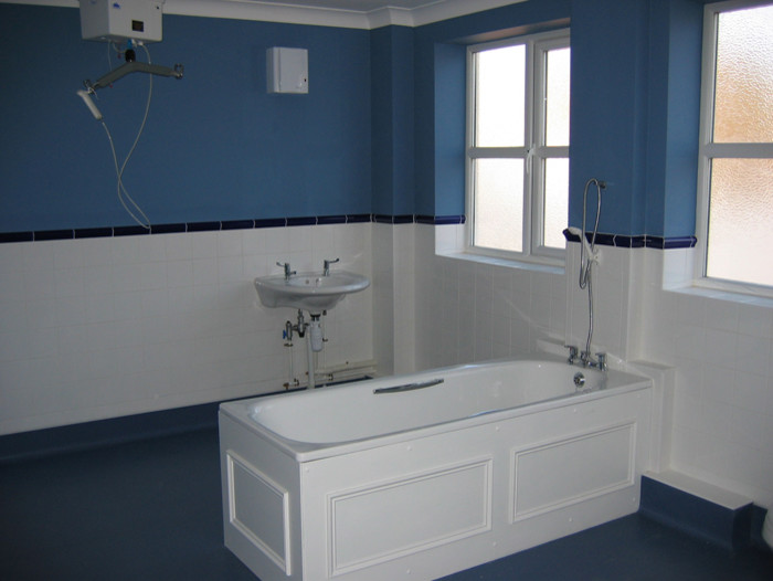 Esempio di una stanza da bagno contemporanea con lavabo sospeso, vasca da incasso, vasca/doccia, piastrelle bianche, piastrelle in ceramica, pareti blu e pavimento in cemento