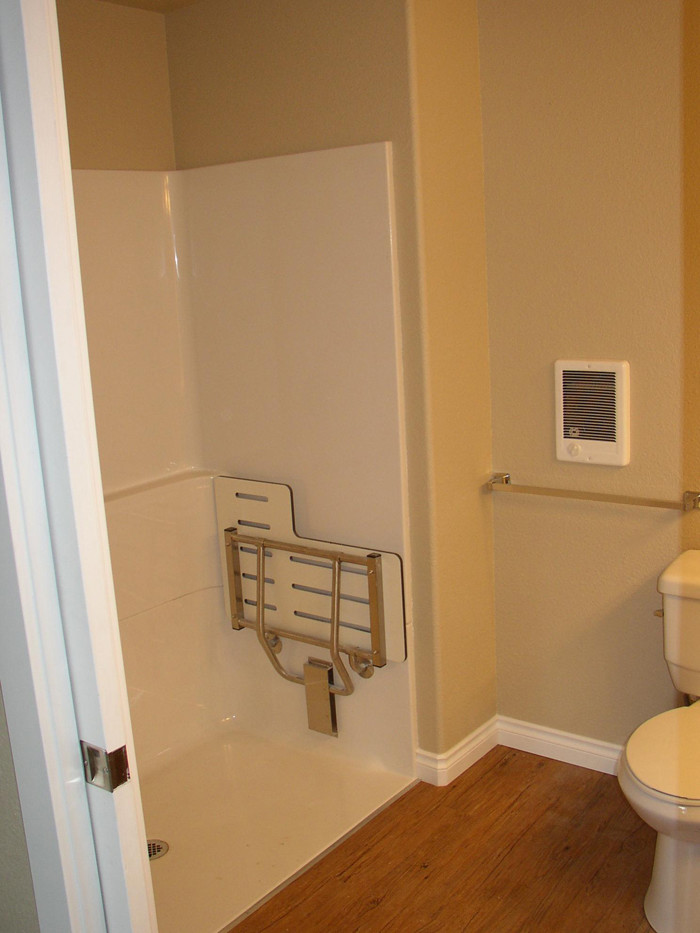 Modelo de cuarto de baño tradicional con ducha empotrada, sanitario de dos piezas, paredes beige y suelo de linóleo