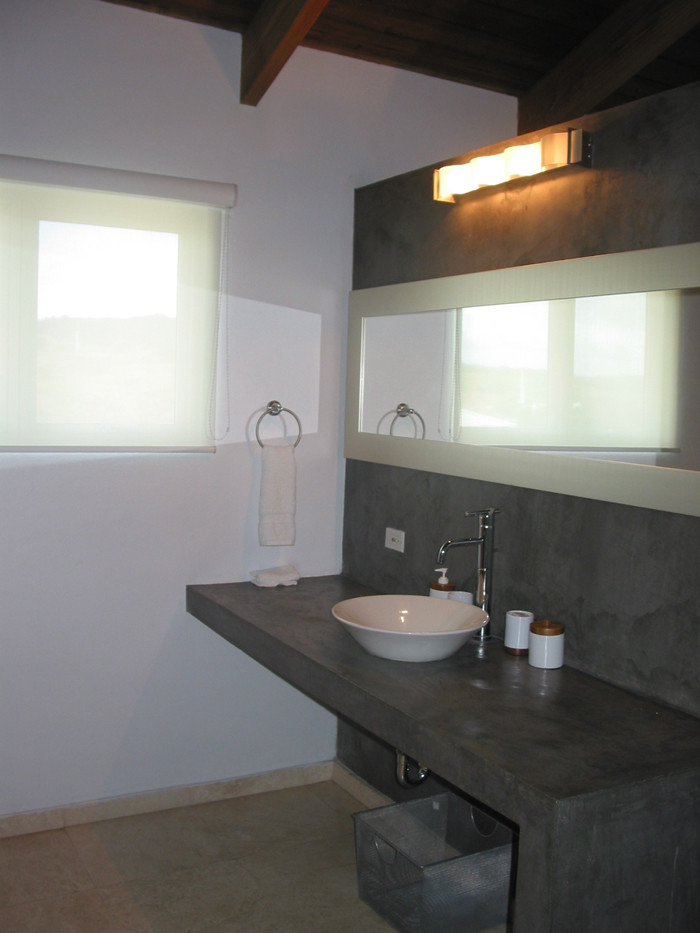 Diseño de cuarto de baño moderno con lavabo sobreencimera, encimera de cemento, baldosas y/o azulejos beige, baldosas y/o azulejos de porcelana, paredes grises y suelo de baldosas de porcelana