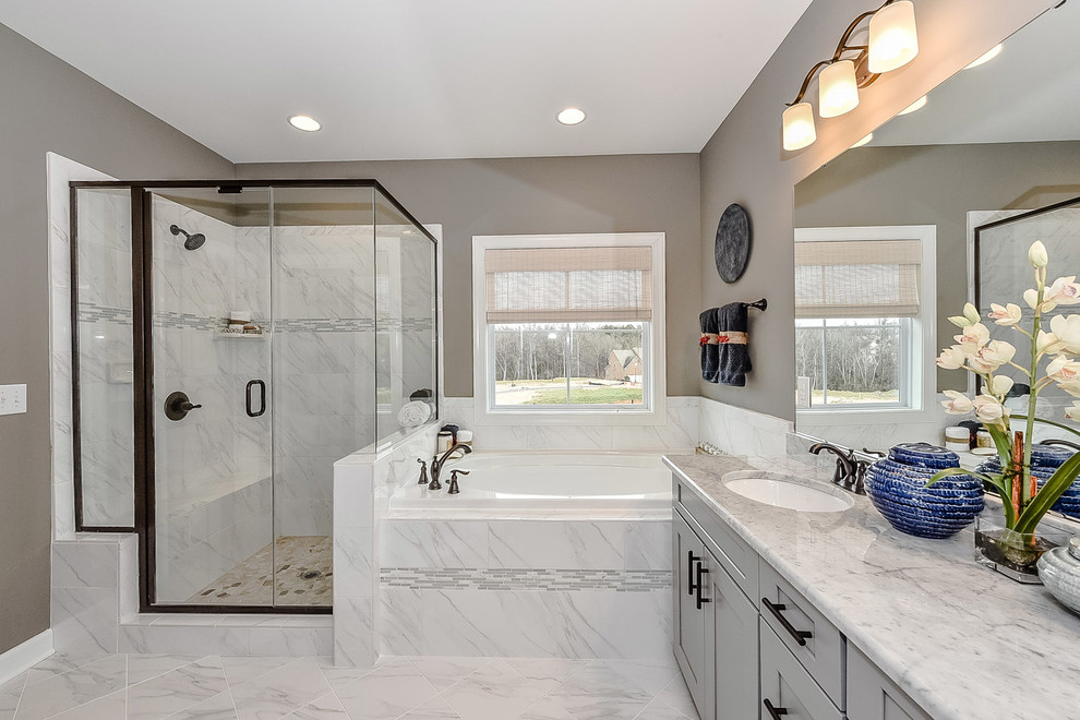 This is an example of a medium sized farmhouse ensuite bathroom in Charlotte with recessed-panel cabinets, grey cabinets, a built-in bath, an alcove shower, grey tiles, porcelain tiles, grey walls, porcelain flooring, quartz worktops, a submerged sink, grey floors and a hinged door.