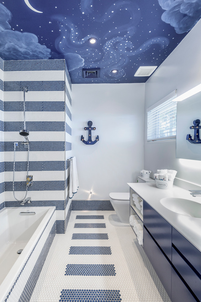Inspiration för ett litet funkis badrum för barn, med släta luckor, blå skåp, ett badkar i en alkov, en dusch/badkar-kombination, en toalettstol med hel cisternkåpa, flerfärgad kakel, mosaik, flerfärgade väggar, mosaikgolv, ett integrerad handfat, bänkskiva i akrylsten och med dusch som är öppen