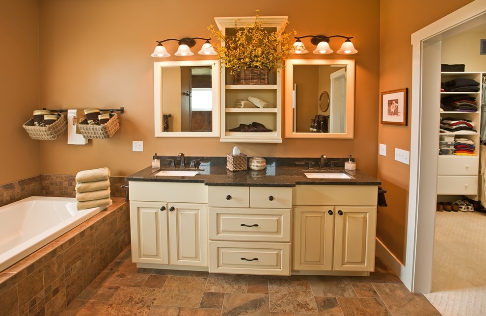 Mid-sized elegant master brown tile porcelain tile and brown floor drop-in bathtub photo in Other with raised-panel cabinets, beige cabinets, brown walls, an undermount sink and granite countertops