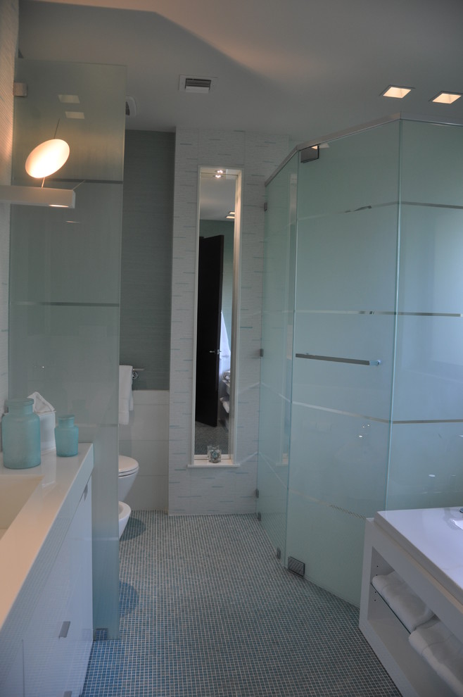 Kleines Modernes Duschbad mit flächenbündigen Schrankfronten, weißen Schränken, Eckdusche, Toilette mit Aufsatzspülkasten, weißen Fliesen, bunten Wänden, integriertem Waschbecken, buntem Boden und Falttür-Duschabtrennung in Miami