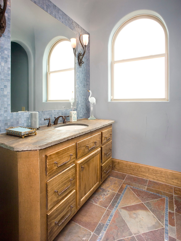 Inspiration for a mid-sized mediterranean 3/4 blue tile slate floor bathroom remodel in Houston with recessed-panel cabinets, medium tone wood cabinets, marble countertops, a one-piece toilet, an undermount sink and blue walls
