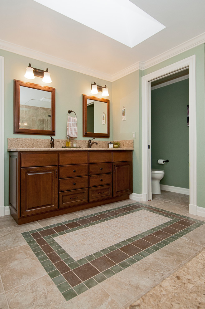 Foto på ett amerikanskt badrum, med ett undermonterad handfat, luckor med upphöjd panel, skåp i mellenmörkt trä, bänkskiva i kvarts, beige kakel, porslinskakel, gröna väggar och klinkergolv i porslin