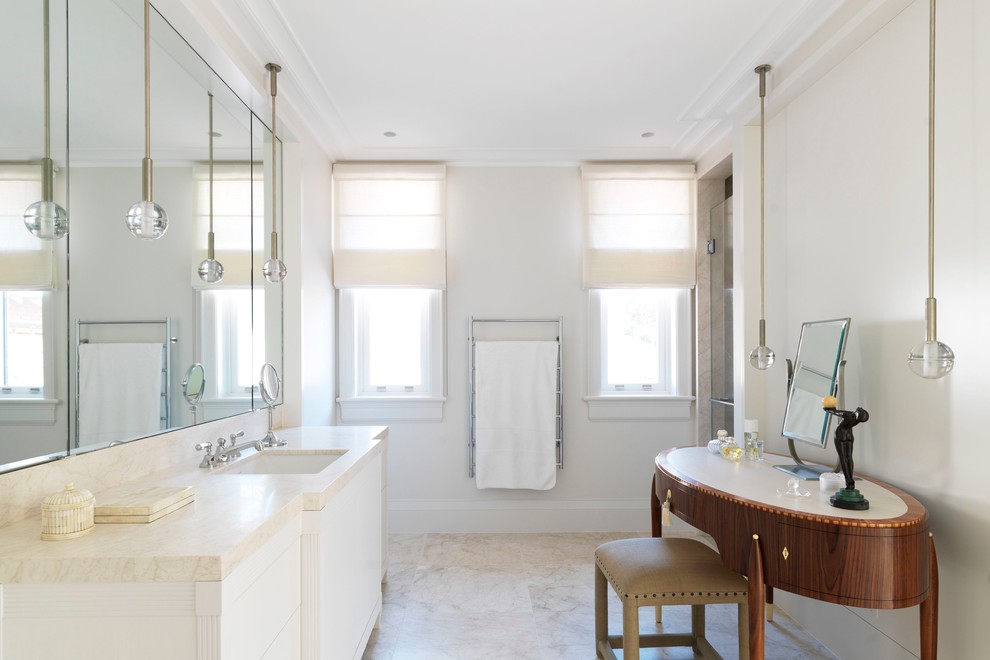 Cette photo montre une salle de bain chic avec un lavabo encastré, un plan de toilette en marbre, une douche d'angle, un carrelage blanc, un placard à porte plane, des portes de placard blanches, un sol en marbre et une fenêtre.