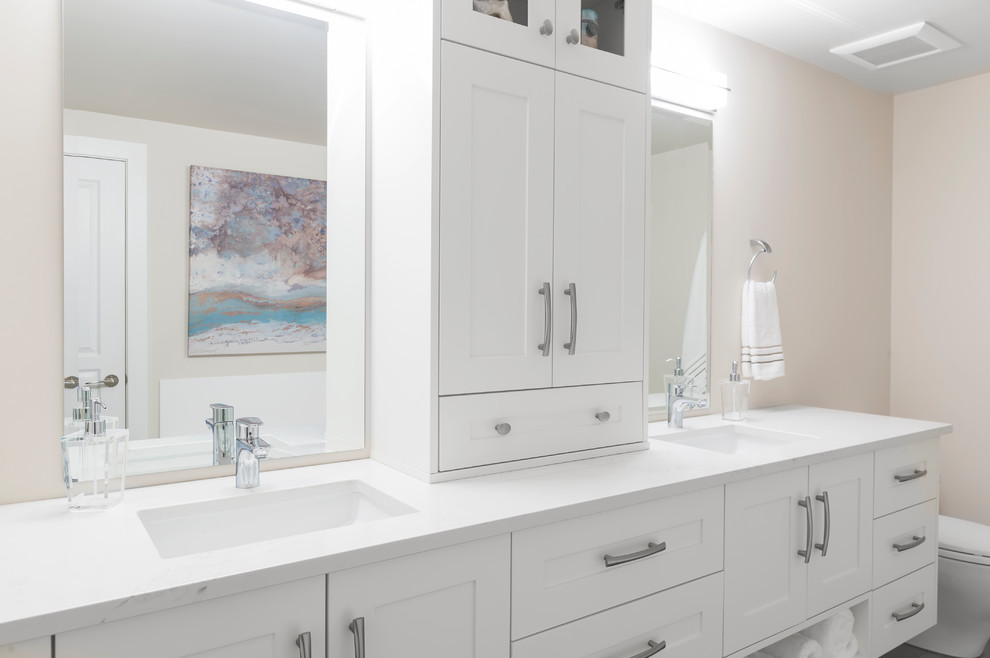 This is an example of a medium sized classic ensuite bathroom in Vancouver with shaker cabinets, white cabinets, a freestanding bath, a corner shower, a one-piece toilet, white tiles, ceramic tiles, beige walls, ceramic flooring, a submerged sink and engineered stone worktops.