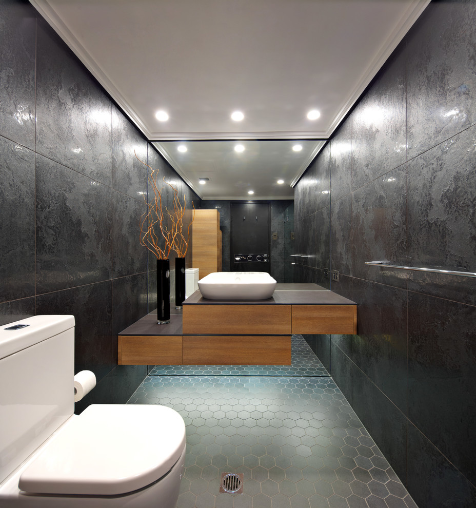 Пример оригинального дизайна: ванная комната среднего размера в стиле модернизм с фасадами цвета дерева среднего тона, инсталляцией, черными стенами, полом из керамической плитки, черной плиткой, столешницей из искусственного камня и настольной раковиной