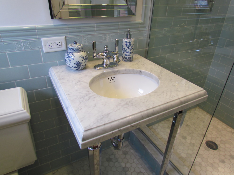 Klassisk inredning av ett litet badrum med dusch, med ett konsol handfat, marmorbänkskiva, en dusch i en alkov, blå kakel, keramikplattor och marmorgolv