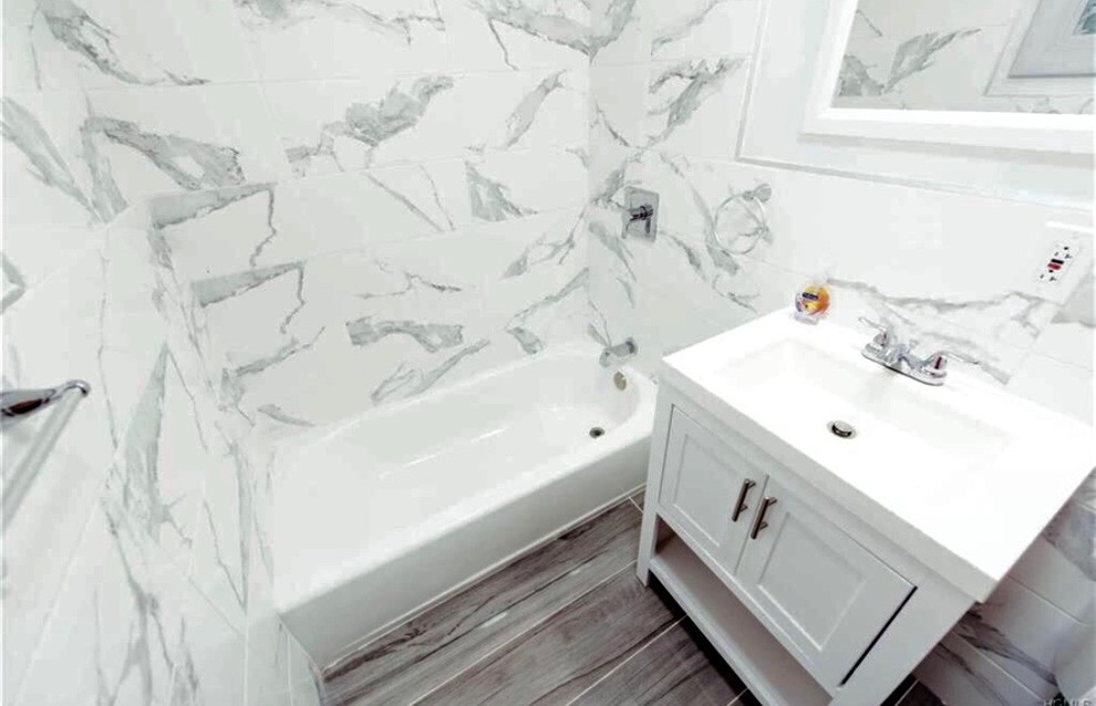 Exempel på ett litet modernt vit vitt badrum, med skåp i shakerstil, grå skåp, ett badkar i en alkov, en dusch/badkar-kombination, en toalettstol med separat cisternkåpa, vit kakel, marmorkakel, vita väggar, klinkergolv i porslin, ett integrerad handfat, bänkskiva i akrylsten, grått golv och med dusch som är öppen