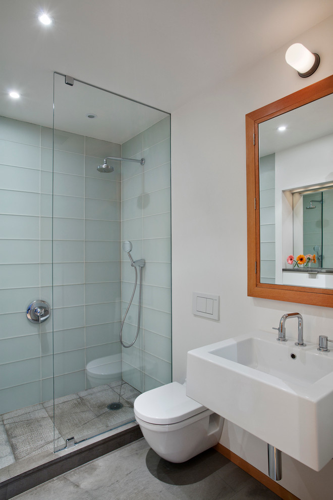 Ejemplo de cuarto de baño contemporáneo con lavabo suspendido, ducha empotrada, sanitario de pared, baldosas y/o azulejos azules, baldosas y/o azulejos de vidrio, paredes blancas y suelo de cemento