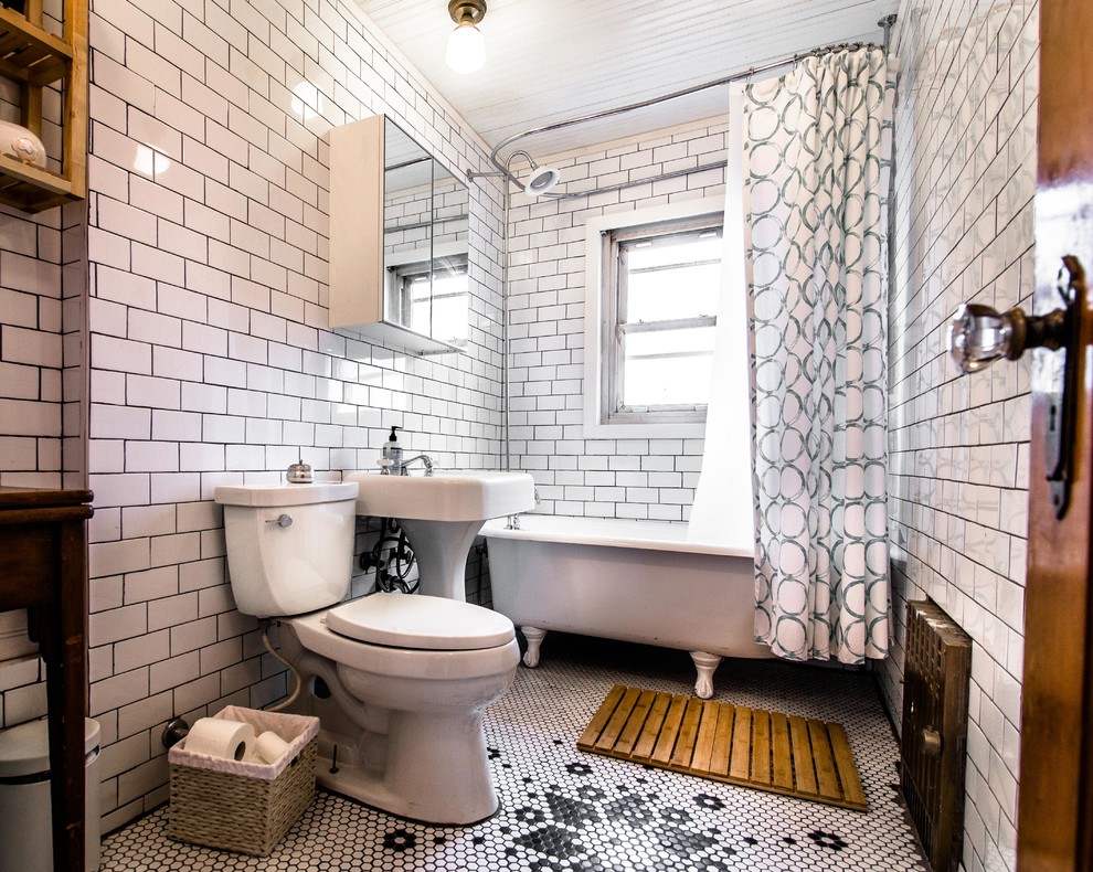 Inredning av ett klassiskt mellanstort badrum, med ett piedestal handfat, ett badkar med tassar, en dusch/badkar-kombination, en toalettstol med hel cisternkåpa, vit kakel, porslinskakel, vita väggar och mosaikgolv