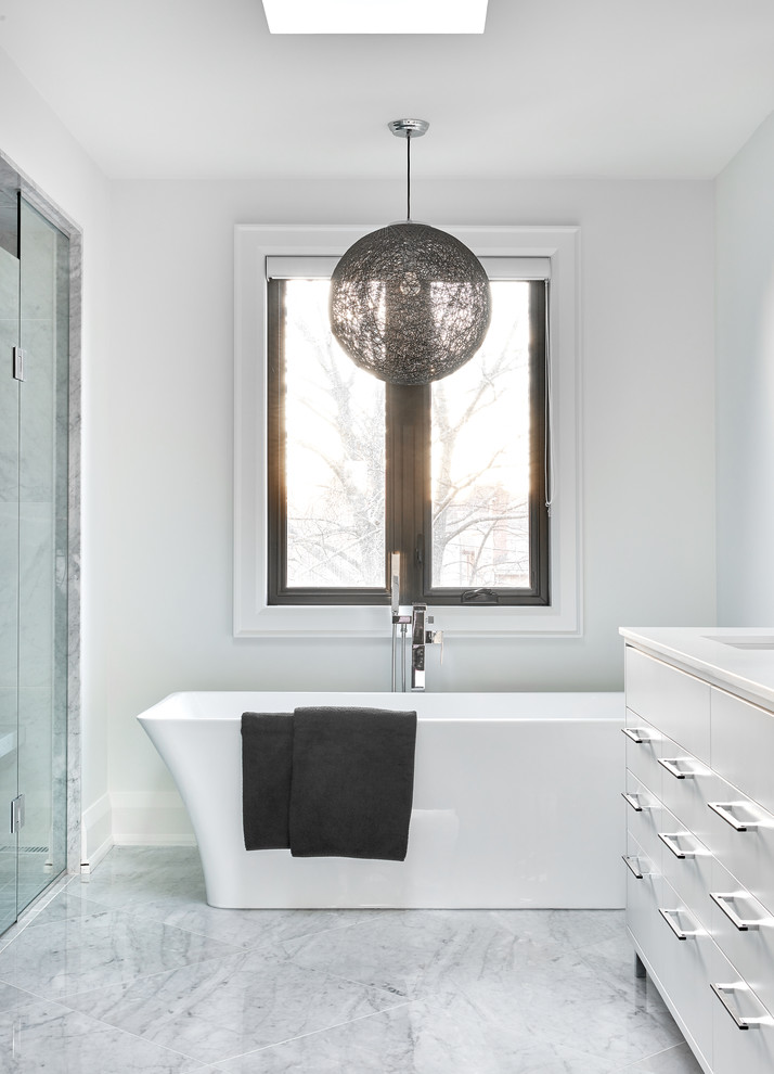 This is an example of a medium sized contemporary ensuite bathroom in Toronto with flat-panel cabinets, white cabinets, a freestanding bath, an alcove shower, grey tiles, marble tiles, white walls, marble flooring, a submerged sink, engineered stone worktops, grey floors and a hinged door.