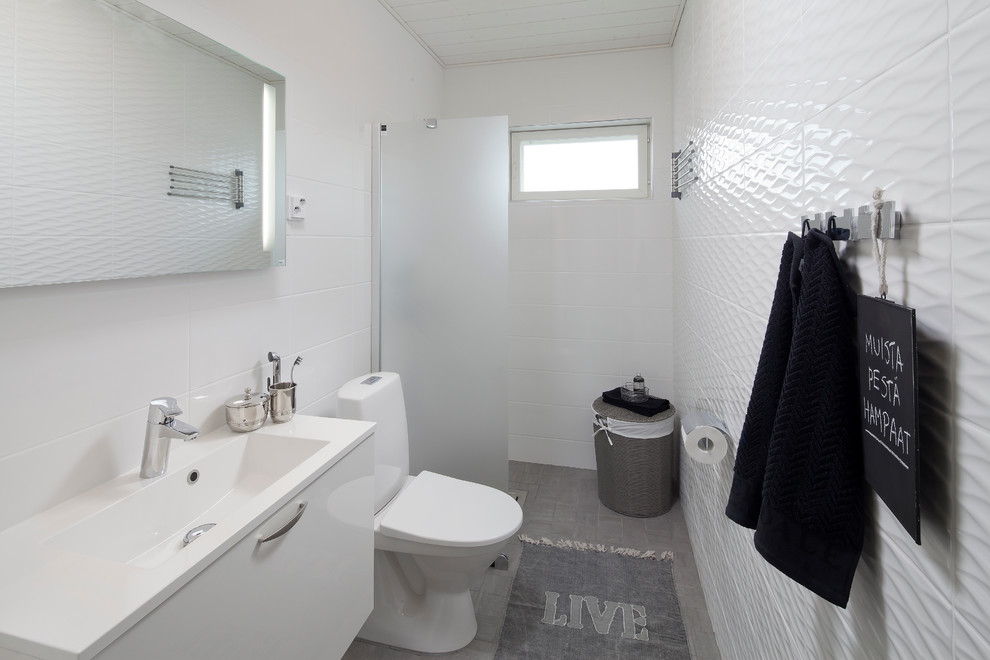 Идея дизайна: ванная комната в скандинавском стиле с плоскими фасадами, белыми фасадами, раздельным унитазом, белой плиткой, белыми стенами, душем без бортиков и серым полом