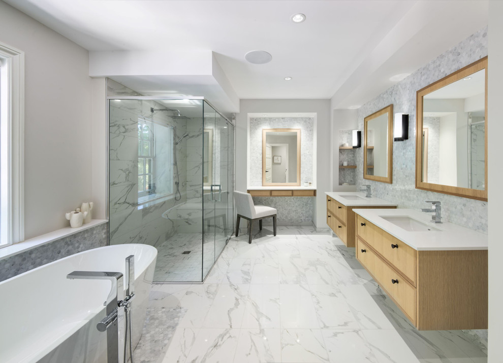 Свежая идея для дизайна: главная ванная комната в современном стиле с светлыми деревянными фасадами, отдельно стоящей ванной, душем без бортиков, серой плиткой, белой плиткой, врезной раковиной, белым полом и белой столешницей - отличное фото интерьера