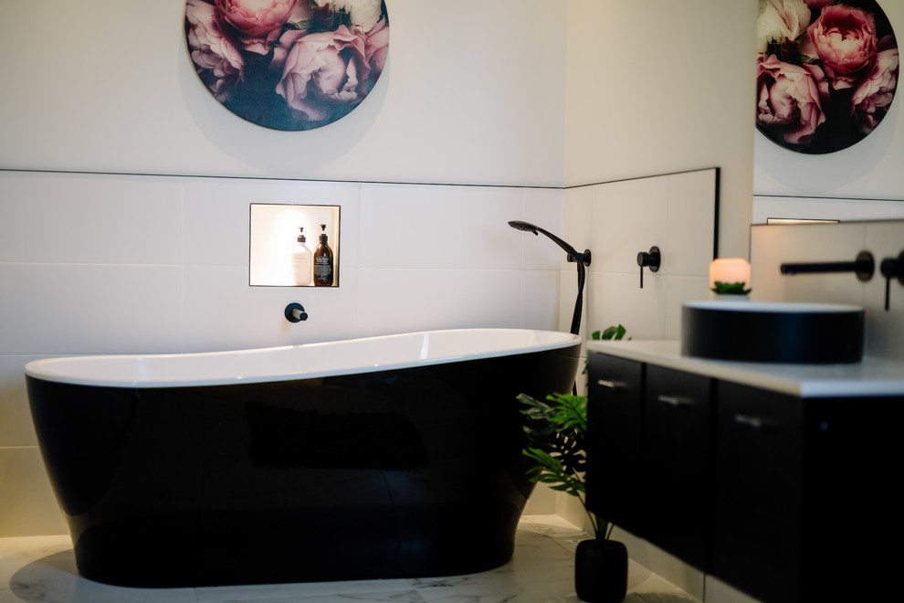 Стильный дизайн: ванная комната в стиле кантри с плоскими фасадами, черными фасадами, отдельно стоящей ванной, белой плиткой, белыми стенами, настольной раковиной, бежевым полом и белой столешницей - последний тренд