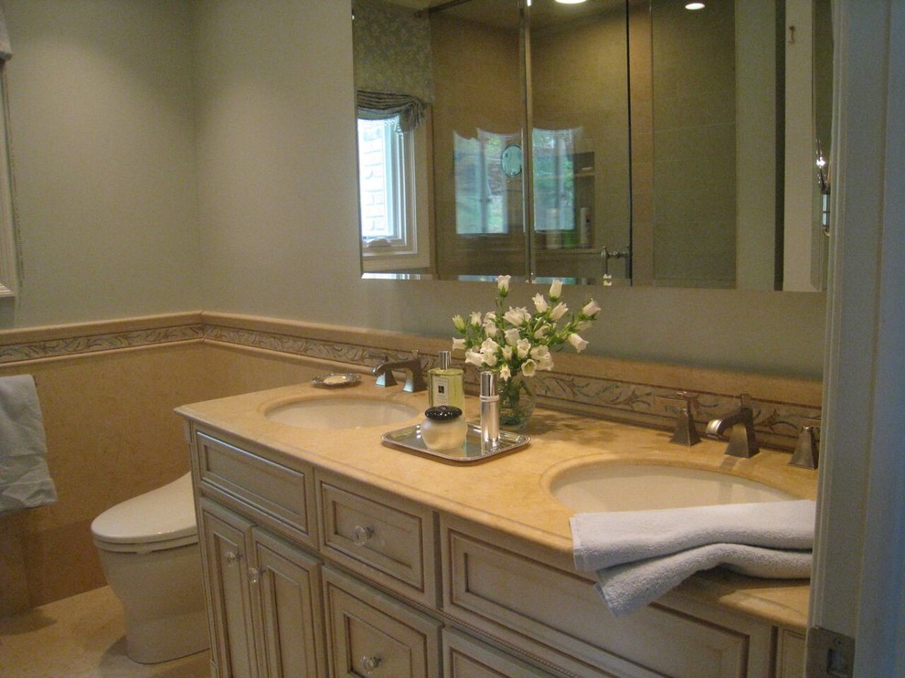 Photo of a large classic ensuite bathroom in New York with beaded cabinets, beige cabinets, a corner shower, a bidet, beige tiles, beige walls, ceramic flooring, a submerged sink and limestone worktops.