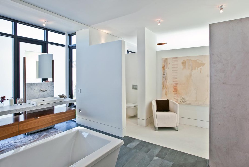 Cette photo montre une grande salle de bain principale tendance en bois brun avec un lavabo posé, une baignoire indépendante, WC suspendus, un placard à porte plane, un plan de toilette en marbre, une douche double, un carrelage bleu, un carrelage de pierre, un mur blanc et un sol en carrelage de porcelaine.
