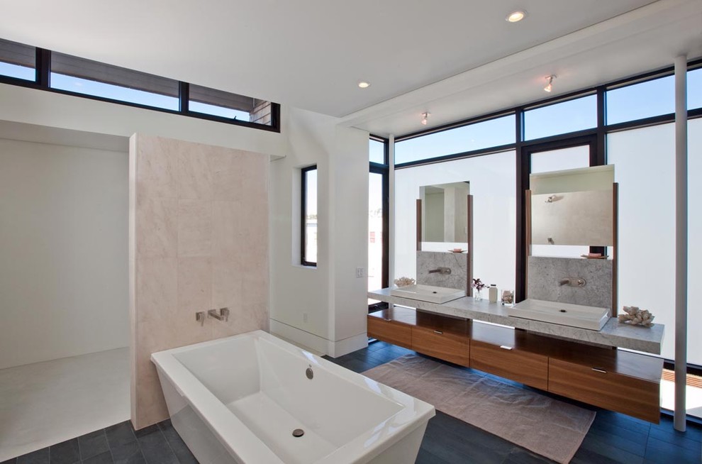 Пример оригинального дизайна: большая главная ванная комната в современном стиле с подвесной раковиной, отдельно стоящей ванной, плоскими фасадами, фасадами цвета дерева среднего тона, мраморной столешницей, двойным душем, унитазом-моноблоком, керамической плиткой, белыми стенами, полом из керамической плитки и бежевой плиткой
