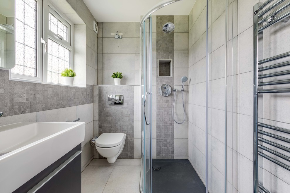 Inspiration för ett mellanstort funkis badrum med dusch, med släta luckor, en vägghängd toalettstol, grå kakel, stenkakel, grå väggar, klinkergolv i porslin, beiget golv, svarta skåp, en hörndusch, ett konsol handfat och dusch med skjutdörr