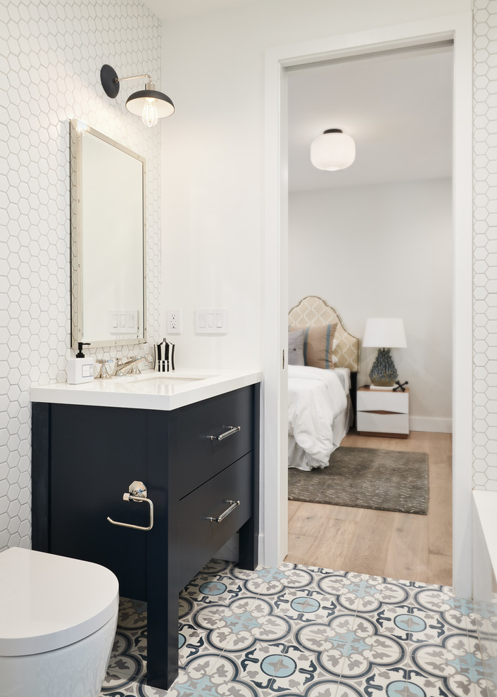 Bild på ett stort vintage vit vitt badrum för barn, med släta luckor, blå skåp, ett platsbyggt badkar, en dusch/badkar-kombination, en vägghängd toalettstol, vit kakel, keramikplattor, vita väggar, cementgolv, ett undermonterad handfat, bänkskiva i kvarts, blått golv och med dusch som är öppen