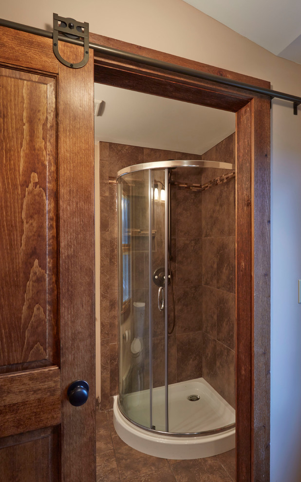 Esempio di una stanza da bagno con doccia country di medie dimensioni con doccia ad angolo, piastrelle beige, piastrelle nere, piastrelle marroni, piastrelle in pietra e pavimento in gres porcellanato