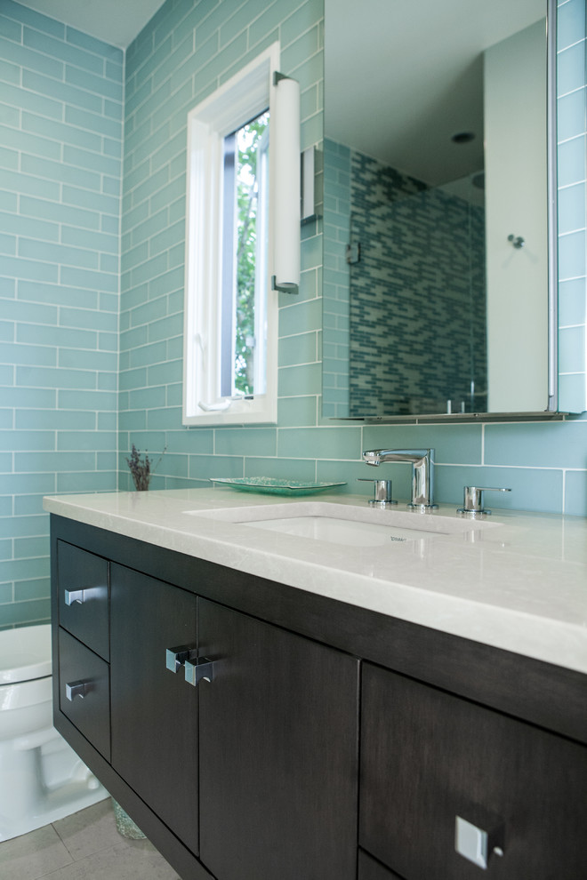 Small eclectic blue tile and glass tile porcelain tile corner shower photo in New York with flat-panel cabinets, dark wood cabinets, quartz countertops, an undermount sink, a two-piece toilet and blue walls