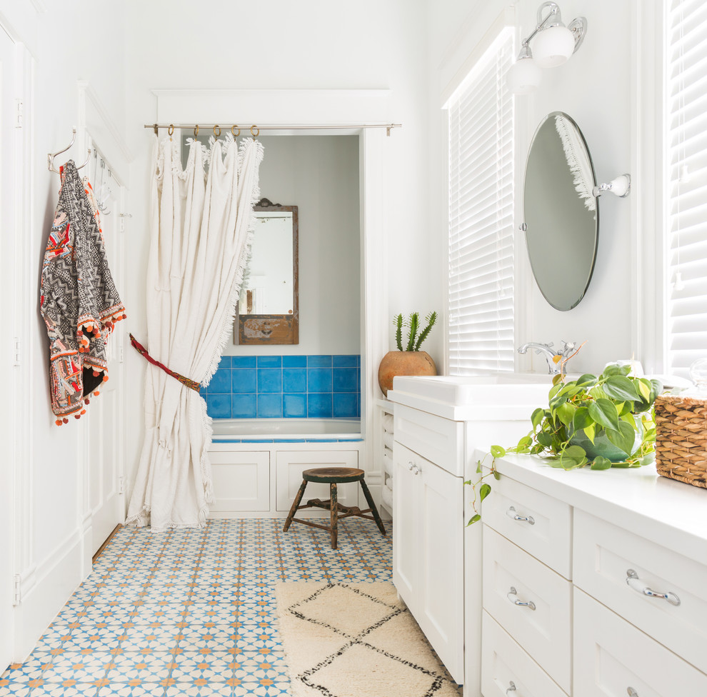 Example of a mid-sized tuscan master blue tile, multicolored tile and ceramic tile multicolored floor and ceramic tile bathroom design in Houston with shaker cabinets, white cabinets, white walls, a drop-in sink and a hinged shower door