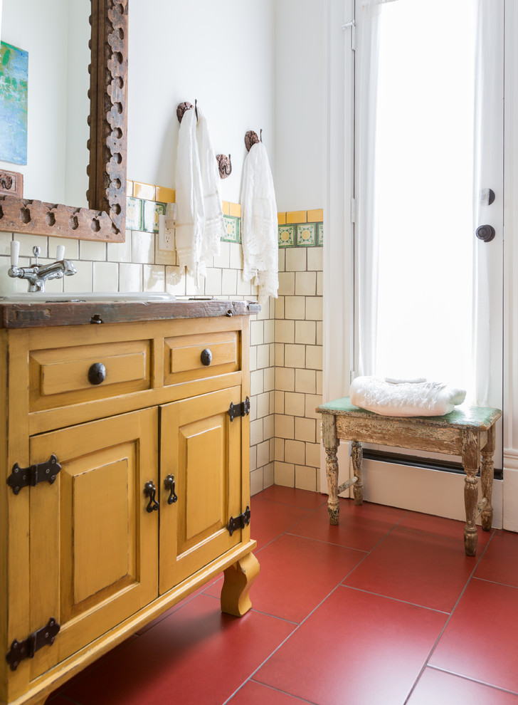 Idéer för att renovera ett mellanstort eklektiskt badrum med dusch, med luckor med upphöjd panel, gula skåp, ett fristående badkar, en dusch/badkar-kombination, beige kakel, keramikplattor, vita väggar, klinkergolv i porslin, ett nedsänkt handfat, rött golv och dusch med duschdraperi