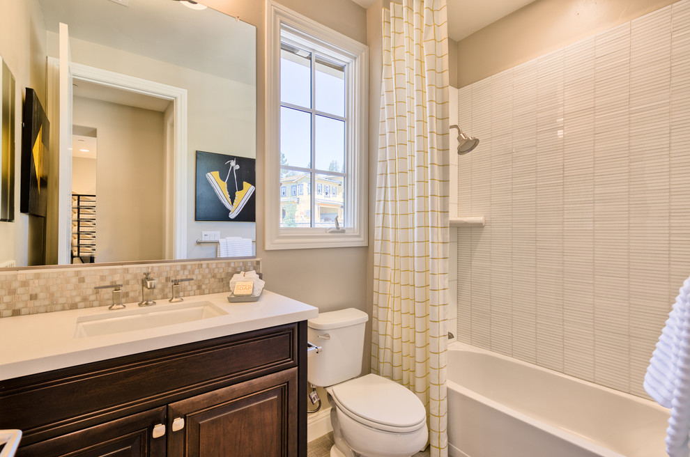 This is an example of a medium sized classic family bathroom in San Francisco with raised-panel cabinets, dark wood cabinets, an alcove bath, a shower/bath combination, a two-piece toilet, beige tiles, mosaic tiles, beige walls, a submerged sink and marble worktops.