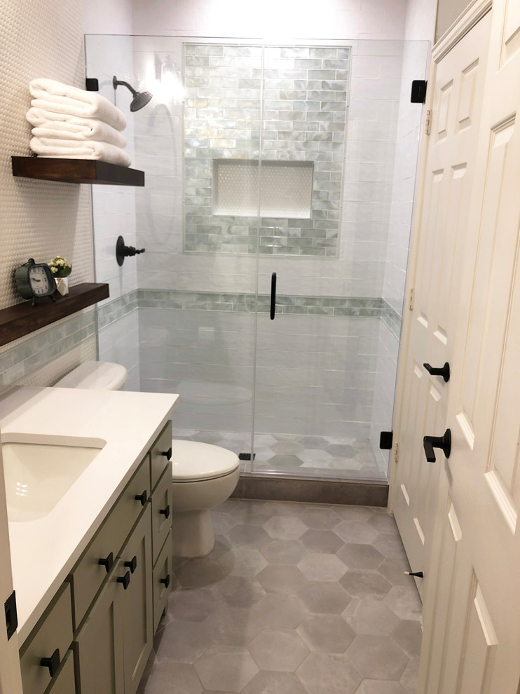 Small mountain style white tile and glass tile porcelain tile and gray floor bathroom photo with shaker cabinets, a one-piece toilet, green walls, an undermount sink, quartz countertops, a hinged shower door and white countertops