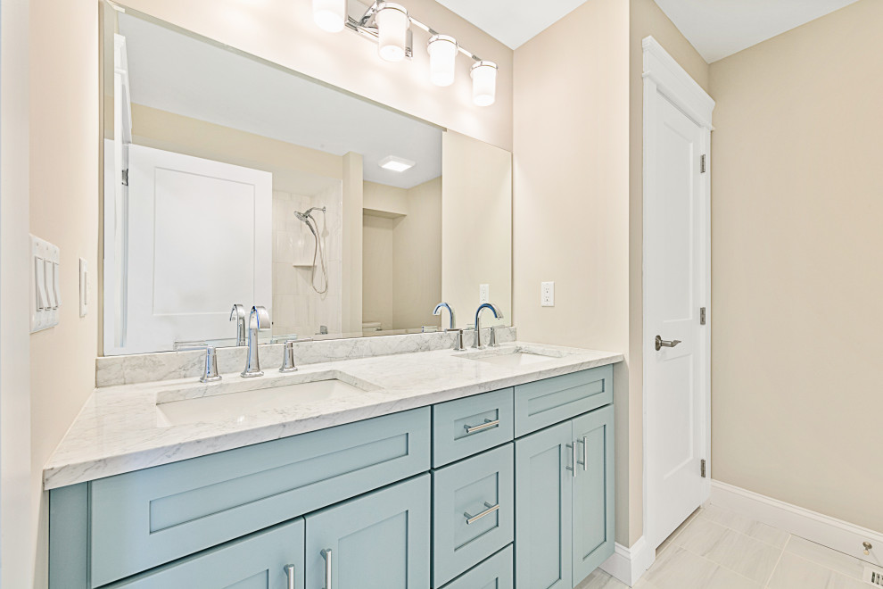 Пример оригинального дизайна: детская ванная комната в морском стиле с фасадами в стиле шейкер, синими фасадами, накладной ванной, душем в нише, унитазом-моноблоком, бежевой плиткой, керамической плиткой, бежевыми стенами, полом из керамической плитки, врезной раковиной, столешницей из гранита, серым полом, шторкой для ванной, серой столешницей, тумбой под две раковины и встроенной тумбой
