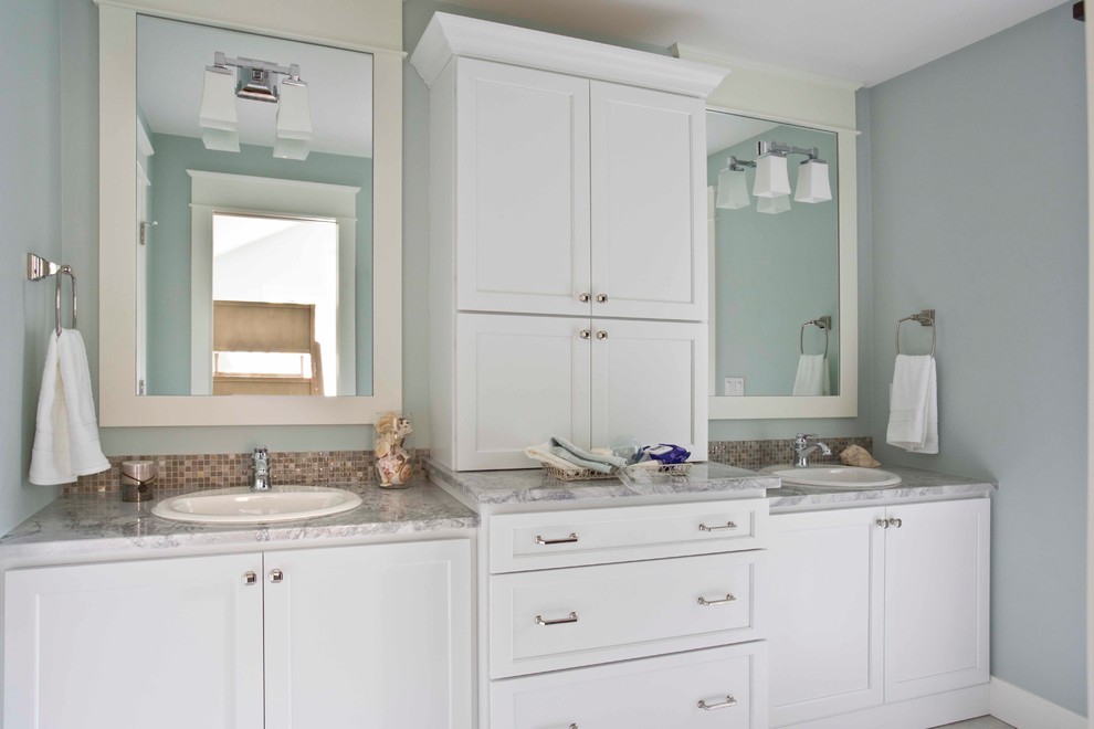 Example of a classic multicolored tile and ceramic tile bathroom design in Grand Rapids with recessed-panel cabinets, white cabinets, blue walls, a drop-in sink and quartz countertops