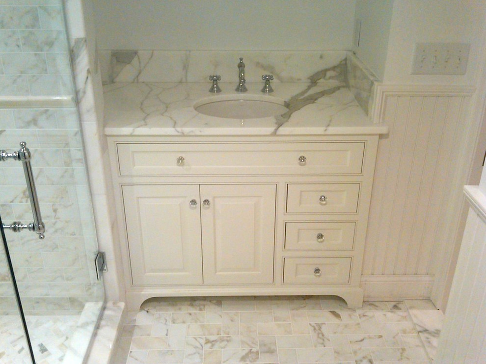 Inredning av ett klassiskt badrum, med ett nedsänkt handfat, luckor med infälld panel, vita skåp, marmorbänkskiva, en öppen dusch, vit kakel, vita väggar och marmorgolv