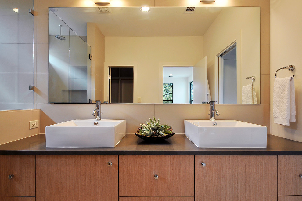 Aménagement d'une salle de bain contemporaine en bois clair avec une vasque, un placard à porte plane et une douche double.