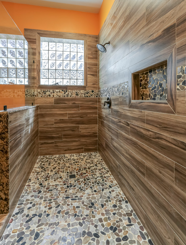 Exemple d'une grande salle de bain principale sud-ouest américain avec un placard à porte affleurante, des portes de placards vertess, une douche double, WC séparés, un carrelage marron, des carreaux de porcelaine, un mur orange, un sol en carrelage de porcelaine, un lavabo encastré et un plan de toilette en granite.