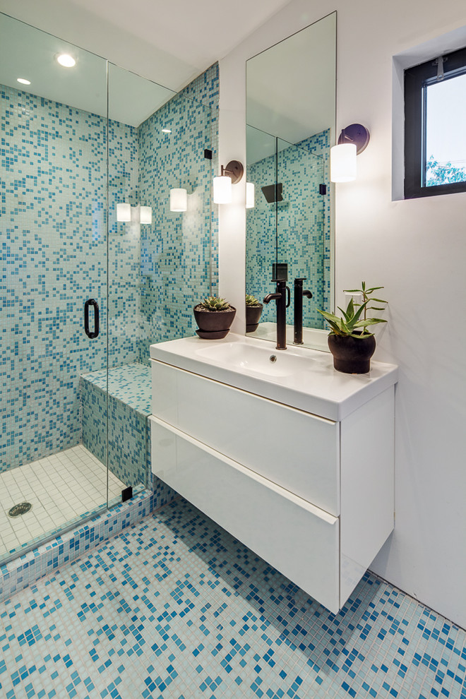 Small contemporary ensuite bathroom in Austin with flat-panel cabinets, white cabinets, a two-piece toilet, blue tiles, mosaic tiles, white walls, mosaic tile flooring and a wall-mounted sink.