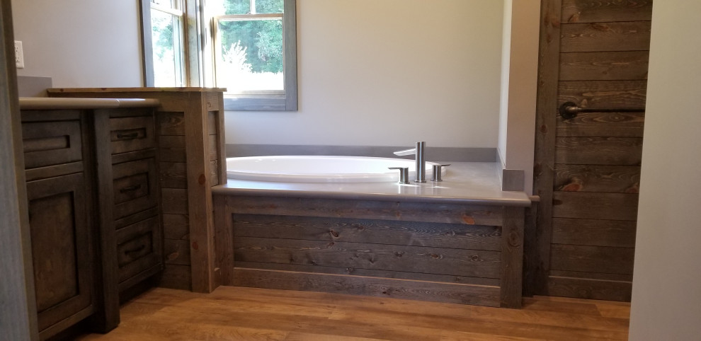 Rustic ensuite bathroom in Grand Rapids with flat-panel cabinets, dark wood cabinets, a built-in bath, an alcove shower, a two-piece toilet, vinyl flooring, a submerged sink, solid surface worktops, brown floors, an open shower, grey worktops, an enclosed toilet, a single sink and a built in vanity unit.