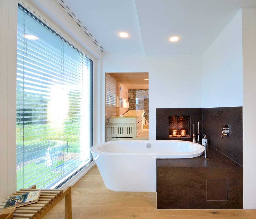 Mittelgroßes Modernes Badezimmer mit freistehender Badewanne, braunen Fliesen, weißer Wandfarbe und braunem Holzboden in Sonstige