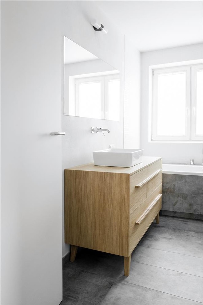 Réalisation d'une salle de bain principale design en bois brun de taille moyenne avec un placard en trompe-l'oeil, une baignoire posée, une douche à l'italienne, WC suspendus, un carrelage gris, des carreaux de céramique, un mur blanc, un sol en carrelage de céramique, une vasque et un plan de toilette en bois.