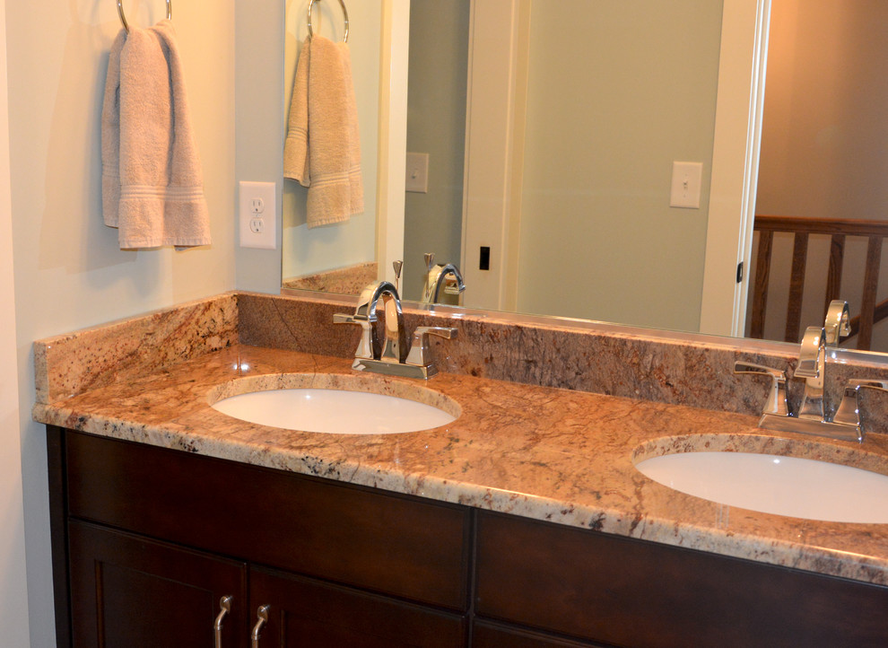 Ispirazione per una stanza da bagno stile americano di medie dimensioni con lavabo sottopiano, ante lisce, ante in legno bruno, top in granito, vasca/doccia e pareti blu