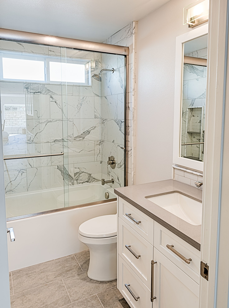 Cette image montre une petite salle d'eau craftsman avec un placard avec porte à panneau encastré, des portes de placard blanches, une baignoire en alcôve, un combiné douche/baignoire, WC séparés, un mur beige, un sol en carrelage de porcelaine, un lavabo encastré, un plan de toilette en quartz modifié, un sol gris, une cabine de douche à porte coulissante et un plan de toilette gris.