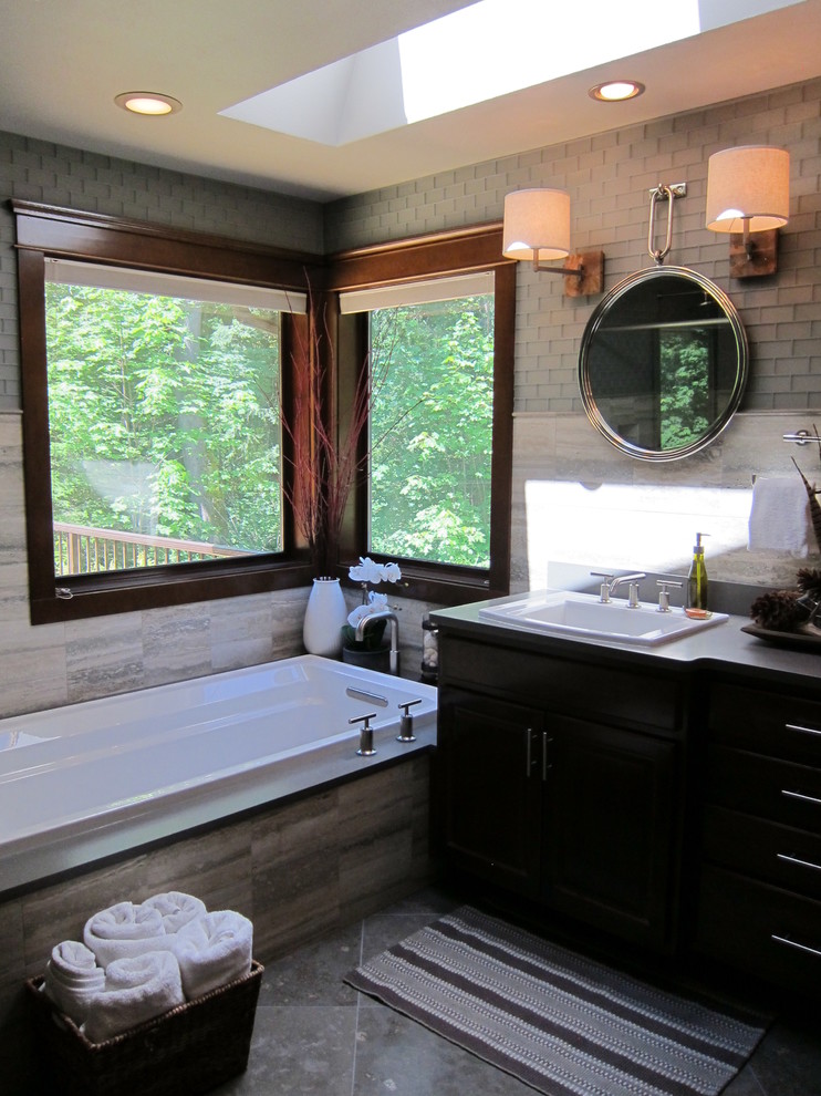 Aménagement d'une grande salle de bain principale contemporaine en bois foncé avec un placard à porte shaker, une baignoire d'angle, une douche ouverte, un carrelage gris, un carrelage en pâte de verre, un mur gris, un sol en calcaire, un lavabo posé et un plan de toilette en quartz modifié.