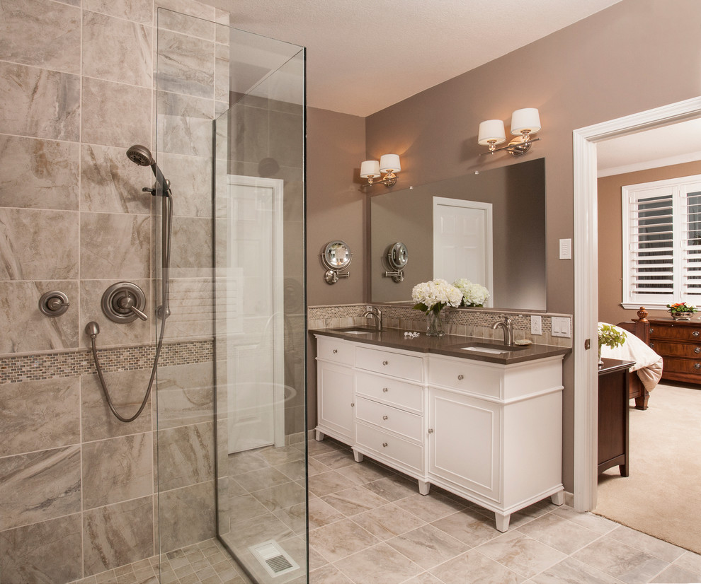 This is an example of a large traditional ensuite bathroom in Seattle with freestanding cabinets, white cabinets, a freestanding bath, a built-in shower, a two-piece toilet, beige tiles, porcelain tiles, brown walls, porcelain flooring, a submerged sink and engineered stone worktops.