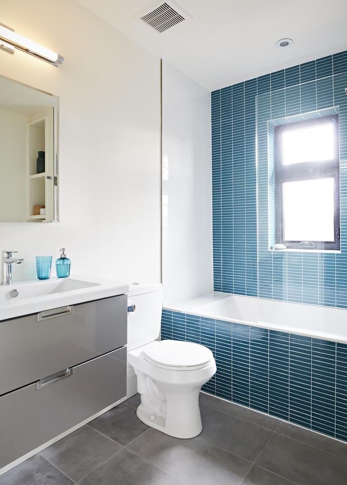 Свежая идея для дизайна: ванная комната среднего размера в современном стиле с плоскими фасадами, серыми фасадами, накладной ванной, душем над ванной, унитазом-моноблоком, синей плиткой, керамической плиткой, белыми стенами, полом из керамической плитки и монолитной раковиной - отличное фото интерьера